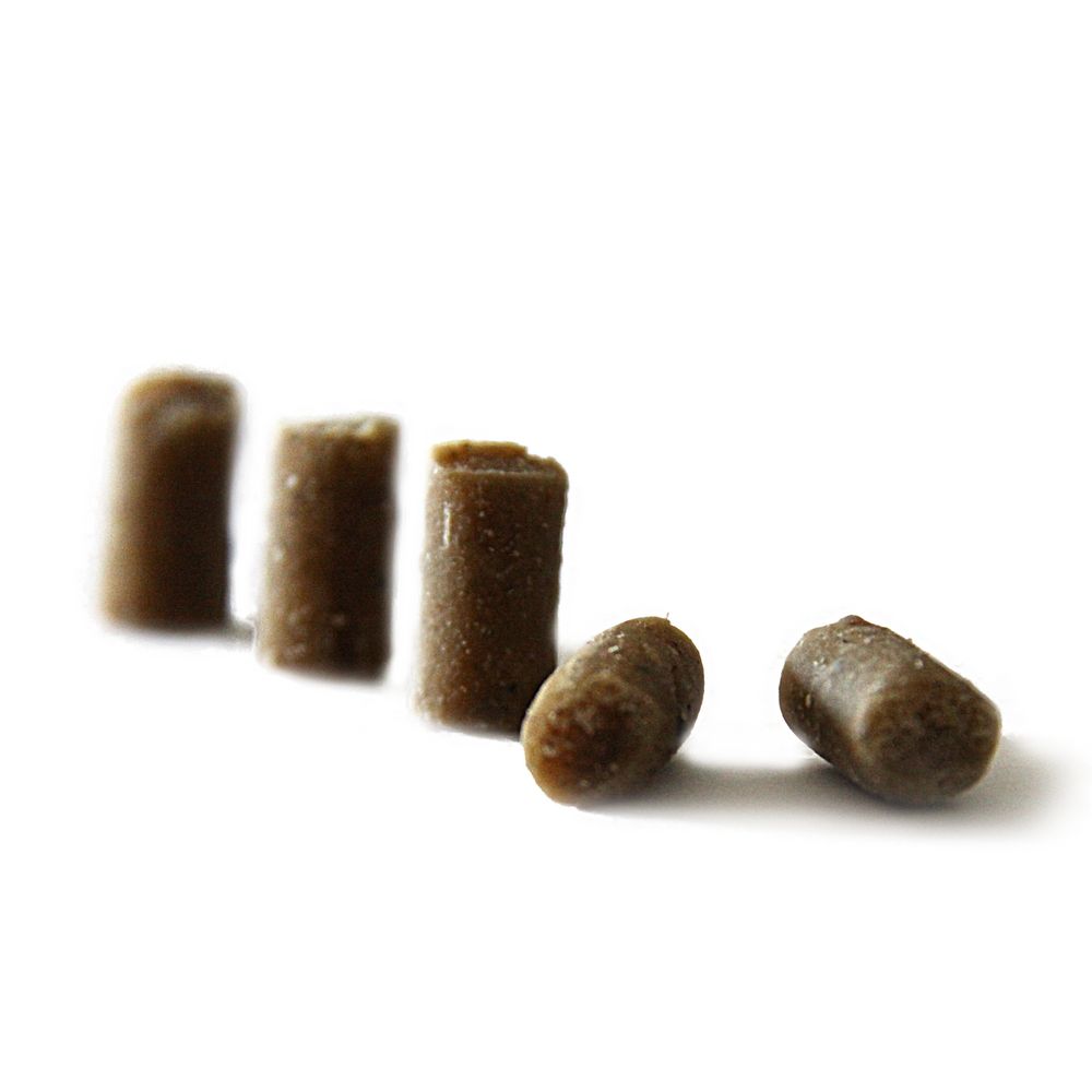 Fünf braune, zylindrische Hundesnacks auf weißem Hintergrund. Einzelne Snacks liegen verstreut.