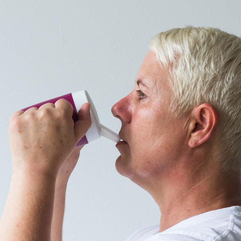 Person trinkt aus einem lila Becher mit Trinkaufsatz. Der Becher wird gehalten.