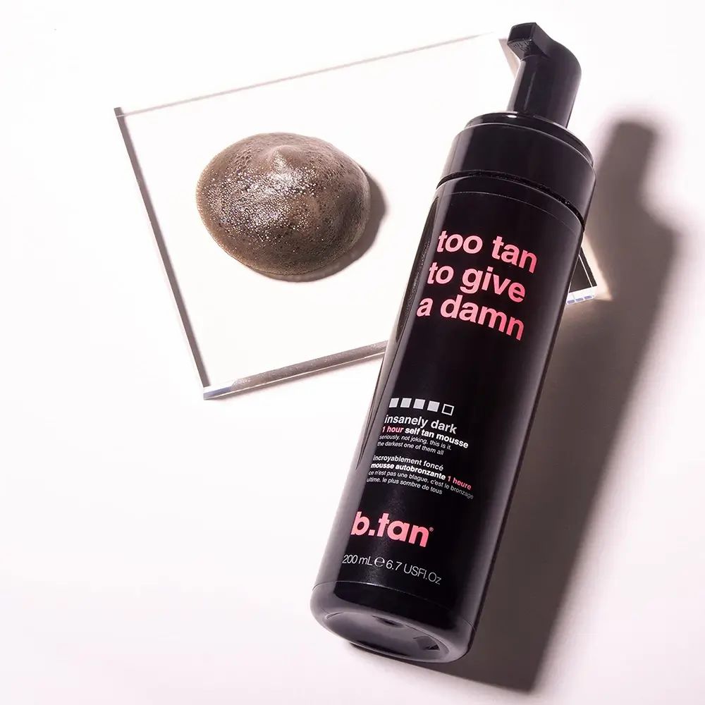Schwarze Flasche mit Aufschrift "too tan to give a damn". Daneben eine Probe des Produkts auf einer Glasplatte.