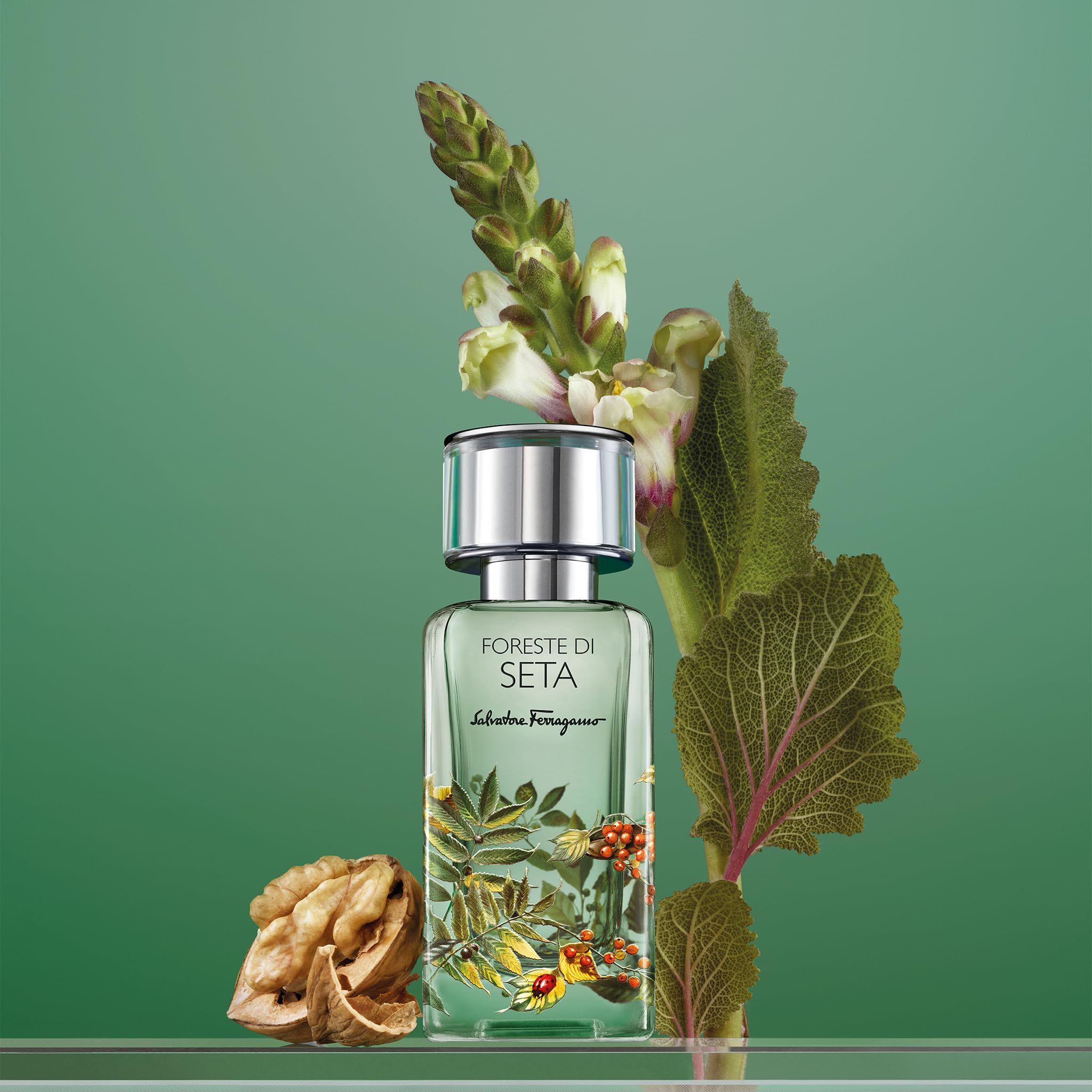 Foreste di Seta EdP Nat. Spray. Flasche vor grünem Hintergrund. Floral-Dekor. Mit Blättern und einer Walnuss dekoriert.