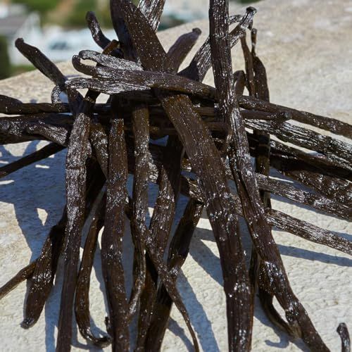 Nahaufnahme von Vanilleschoten. Dunkelbraune, längliche Schoten mit weißem Belag, auf heller Oberfläche.