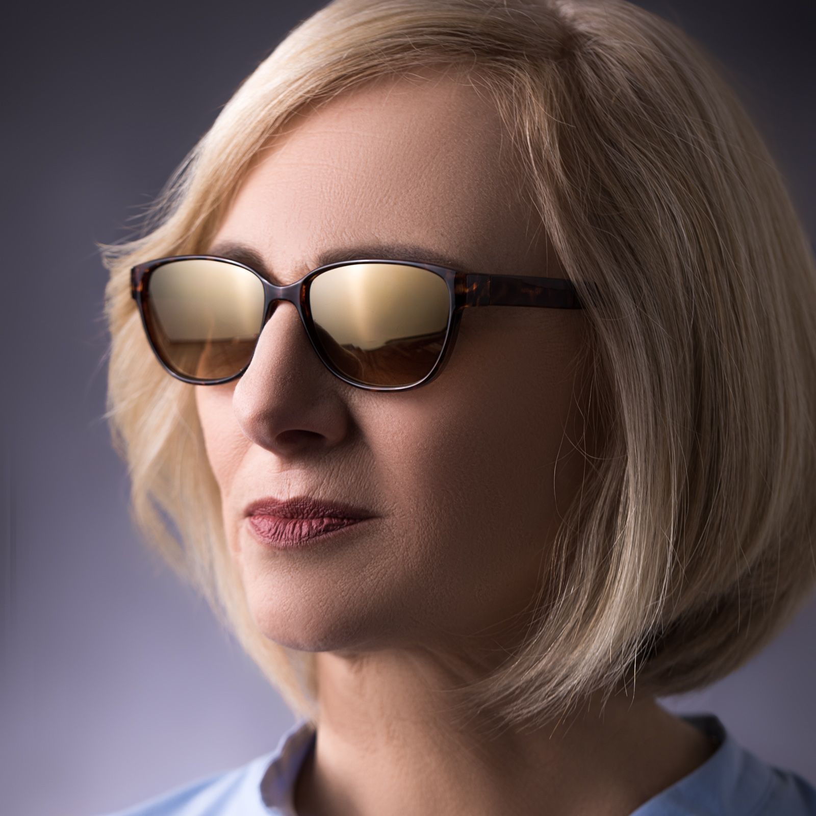 Frau mit Sonnenbrille. Schildpatt-Muster-Rahmen. Nahaufnahme, vor grauem Hintergrund.