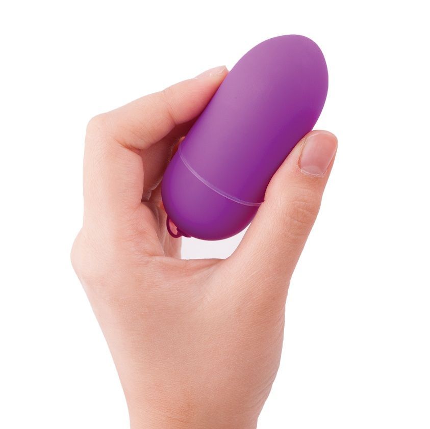 Hand hält ein lila Ei. Das Ei hat eine Schlaufe. Das Produkt ist aus glattem Material.