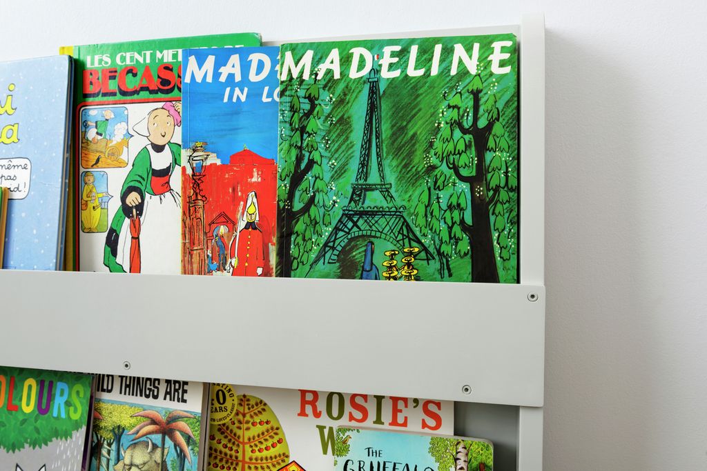 Hellgraues Bücherregal mit Büchern. Bücher mit farbigen Einbänden. Bücher mit Titeln wie "Madeline in Love" und "Rosie's Walk".