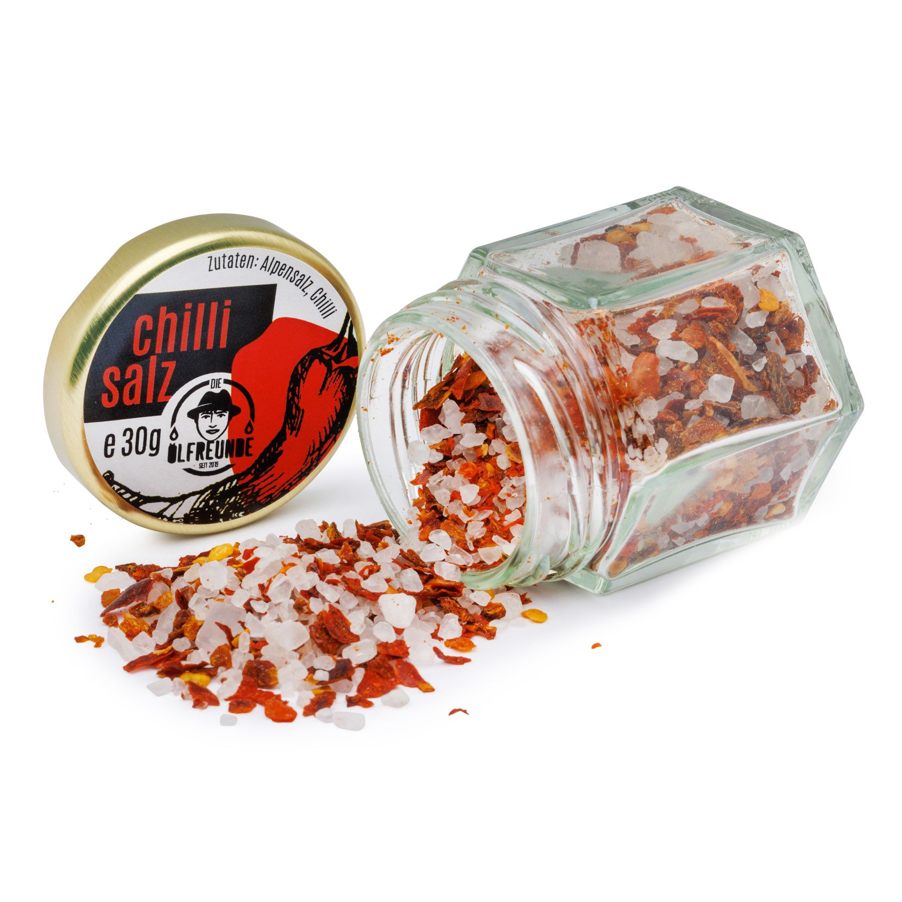 Geöffnetes Glas mit Chilisalz. Deckel daneben. Rotes Chili-Bild auf dem Deckel. Marke: Die Ölfreunden. Salz und Chili-Flocken verstreut.