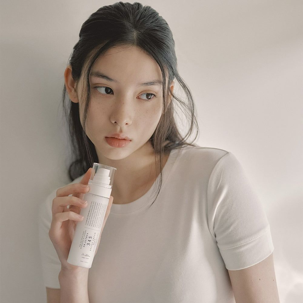 Frau mit weißem T-Shirt hält eine weiße Sprühflasche Dr. Althea 345 Relief Cream Mist.