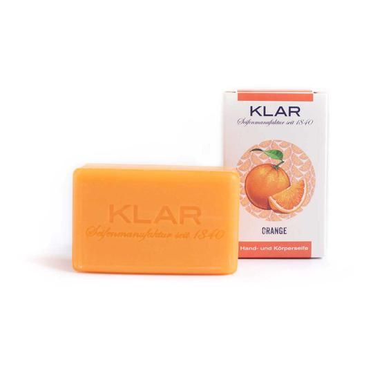 Orangene Seife neben weißem Karton mit Orangendarstellung und Schriftzug "KLAR".