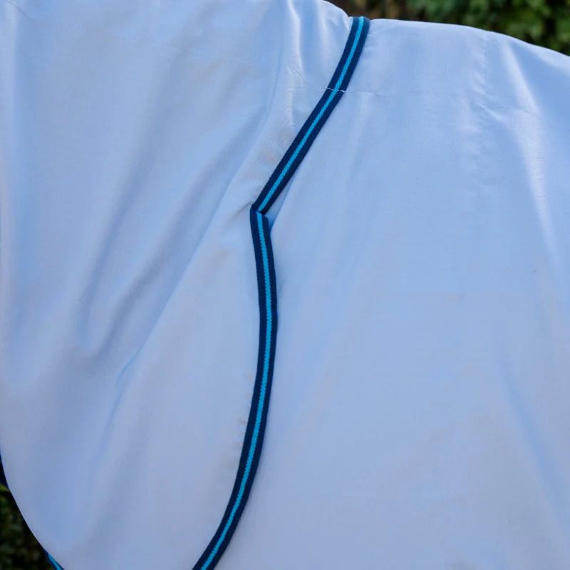 Nahaufnahme einer hellblauen Pferdedecke mit blauen Zierleisten. Die Decke hat eine abgerundete Form.