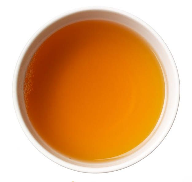 Tasse Kräutertee, Draufsicht. Flüssigkeit orangefarben, in weißer Tasse.