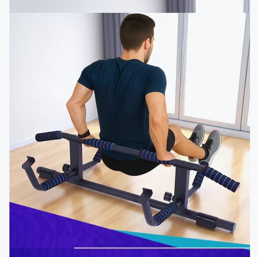 Person sitzt auf einer schwarzen Klimmzugstange mit blauen Griffen. Die Stange steht auf dem Boden.