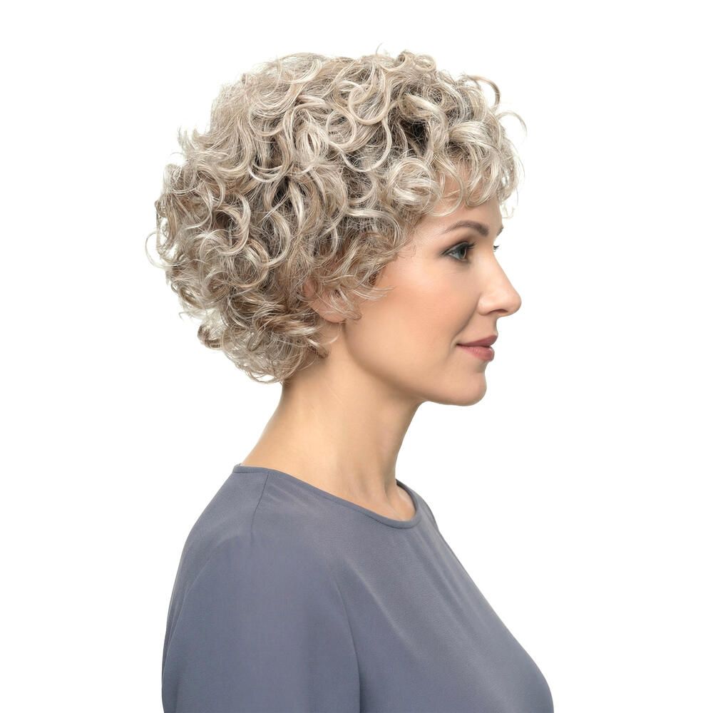 Frau mit Perücke, blond gelockt, Seitenansicht. Graues Oberteil. Blick nach rechts.