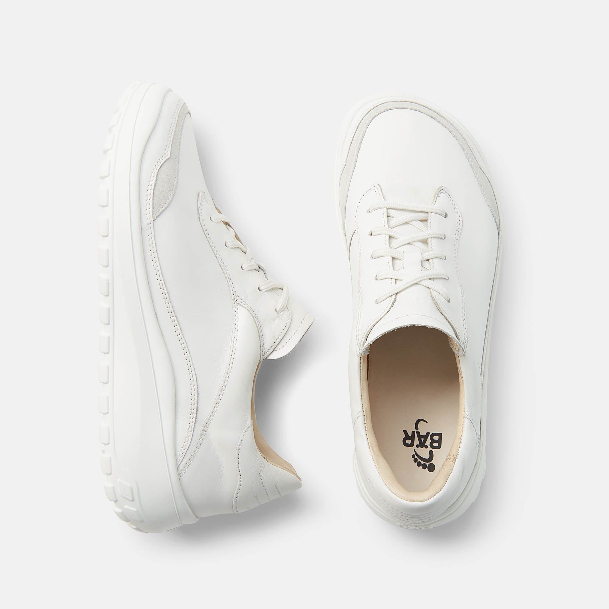 Draufsicht auf zwei weiße Schnürschuhe. Innensohle mit Logo. Runde Sohle, helle Schnürsenkel. Grauer Einsatz.