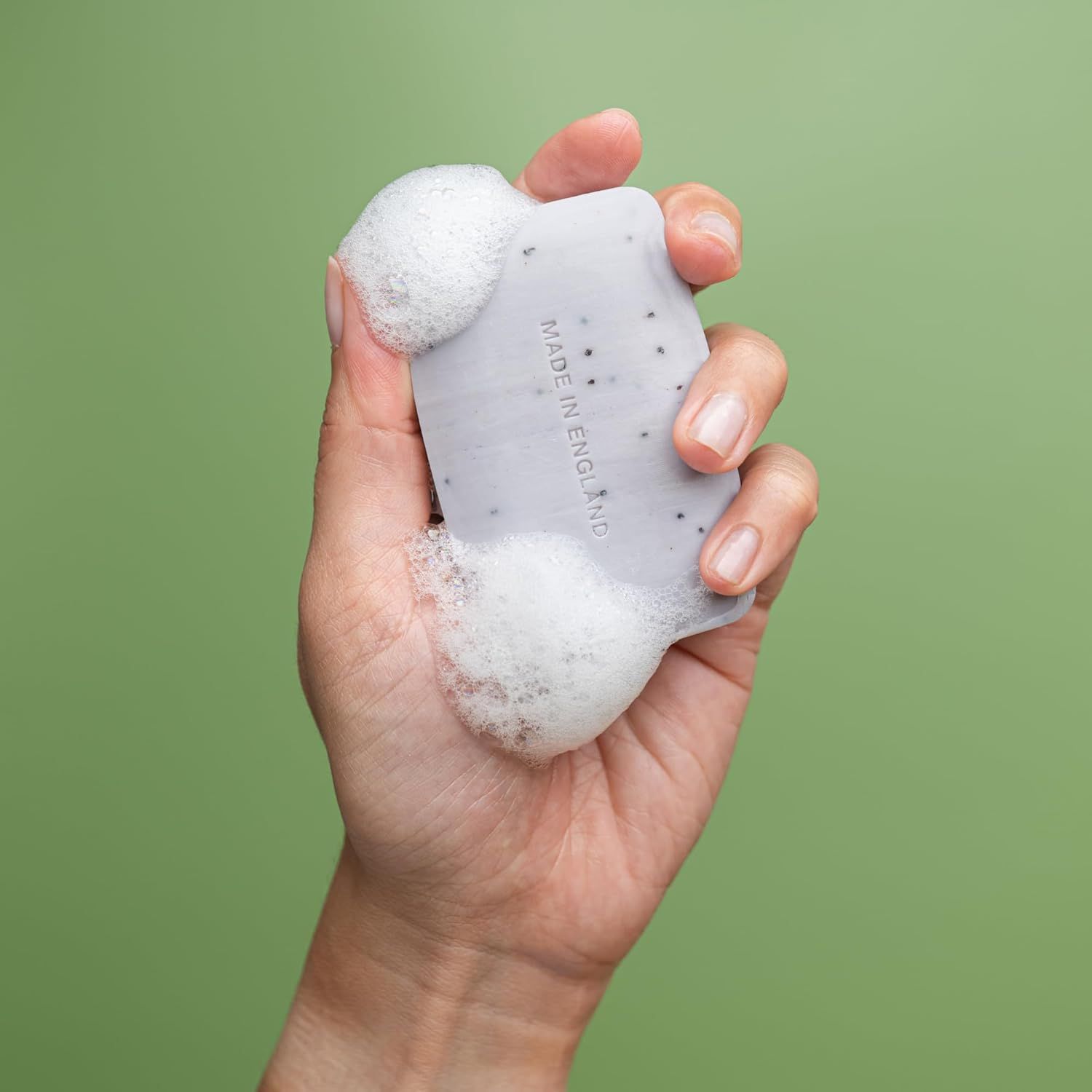 Hand hält Seife mit Schaum. Auf der Seife steht "MADE IN ENGLAND".