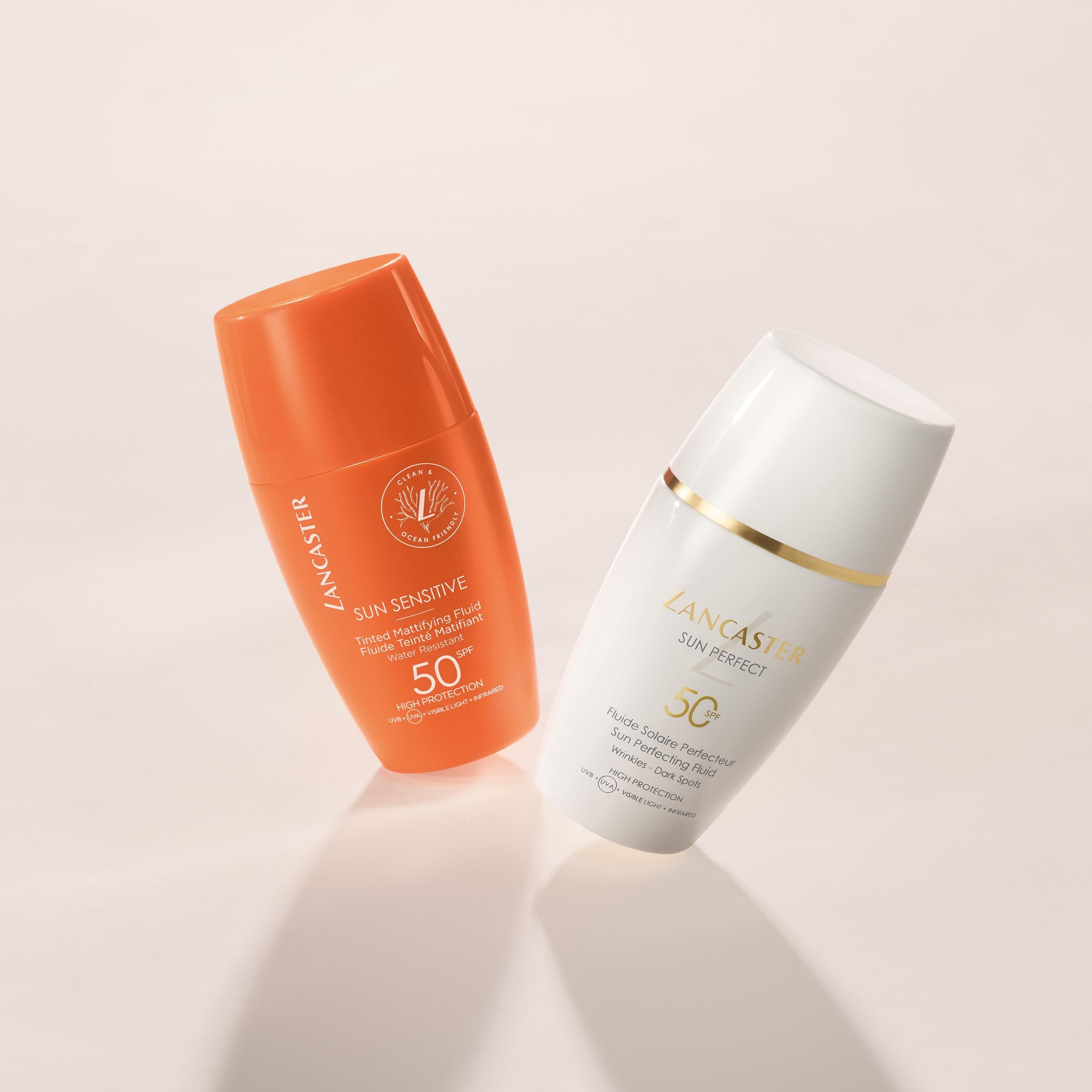 Zwei Flaschen: Orangefarbene Lancaster Sun Sensitive und weiße Lancaster Sun Perfect. Beide mit SPF 50.