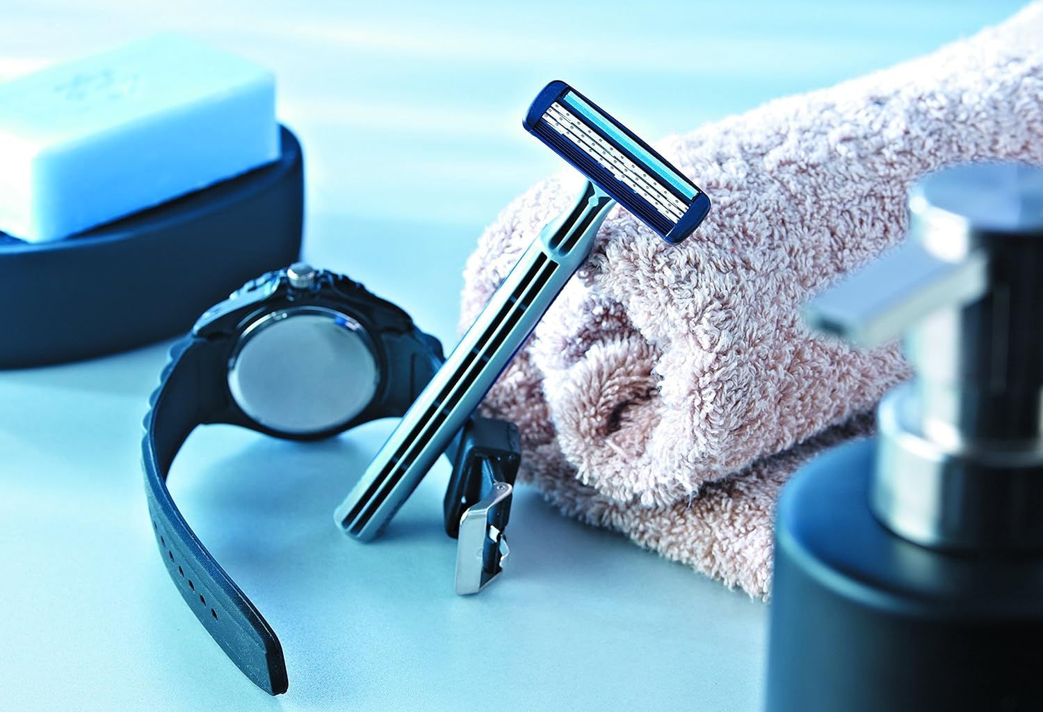 Rasierer, Uhr, Handtuch und Seife. Rasierer liegt auf einem Handtuch.