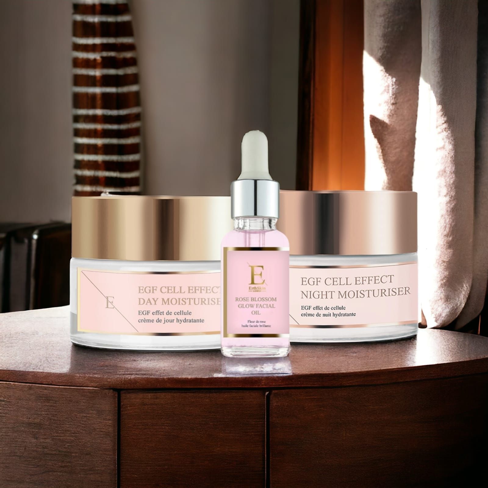 Drei Kosmetikprodukte auf Holzoberfläche. Tages- und Nachtcreme, Gesichtsöl. Rosa Etiketten, goldene Deckel. "EGF Cell Effect" und "Rose Blossom Glow".