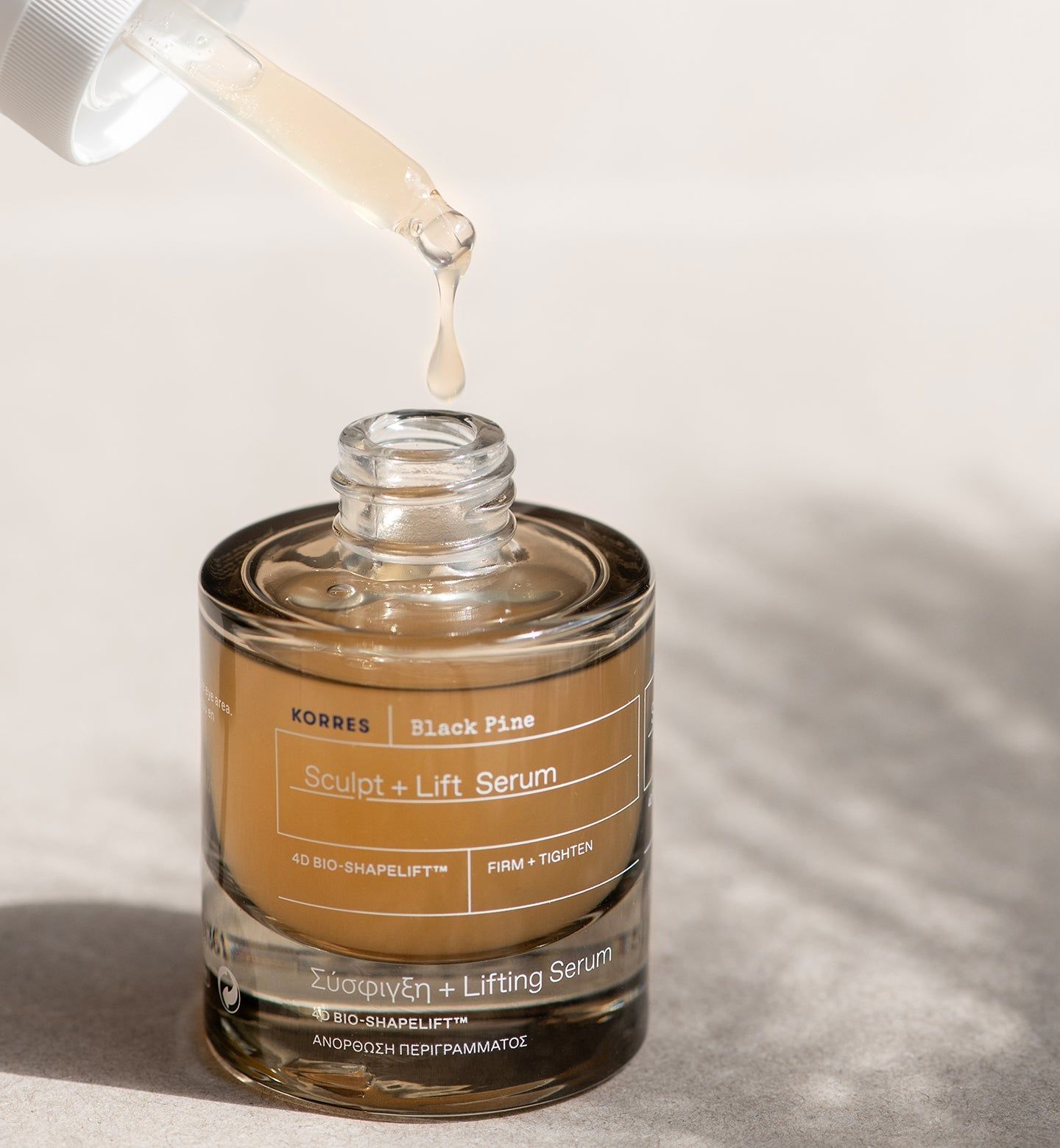 KORRES Black Pine Serum, Flasche mit Pipette. Serum tropft aus der Pipette in die Flasche. Produktname und Logo sichtbar.