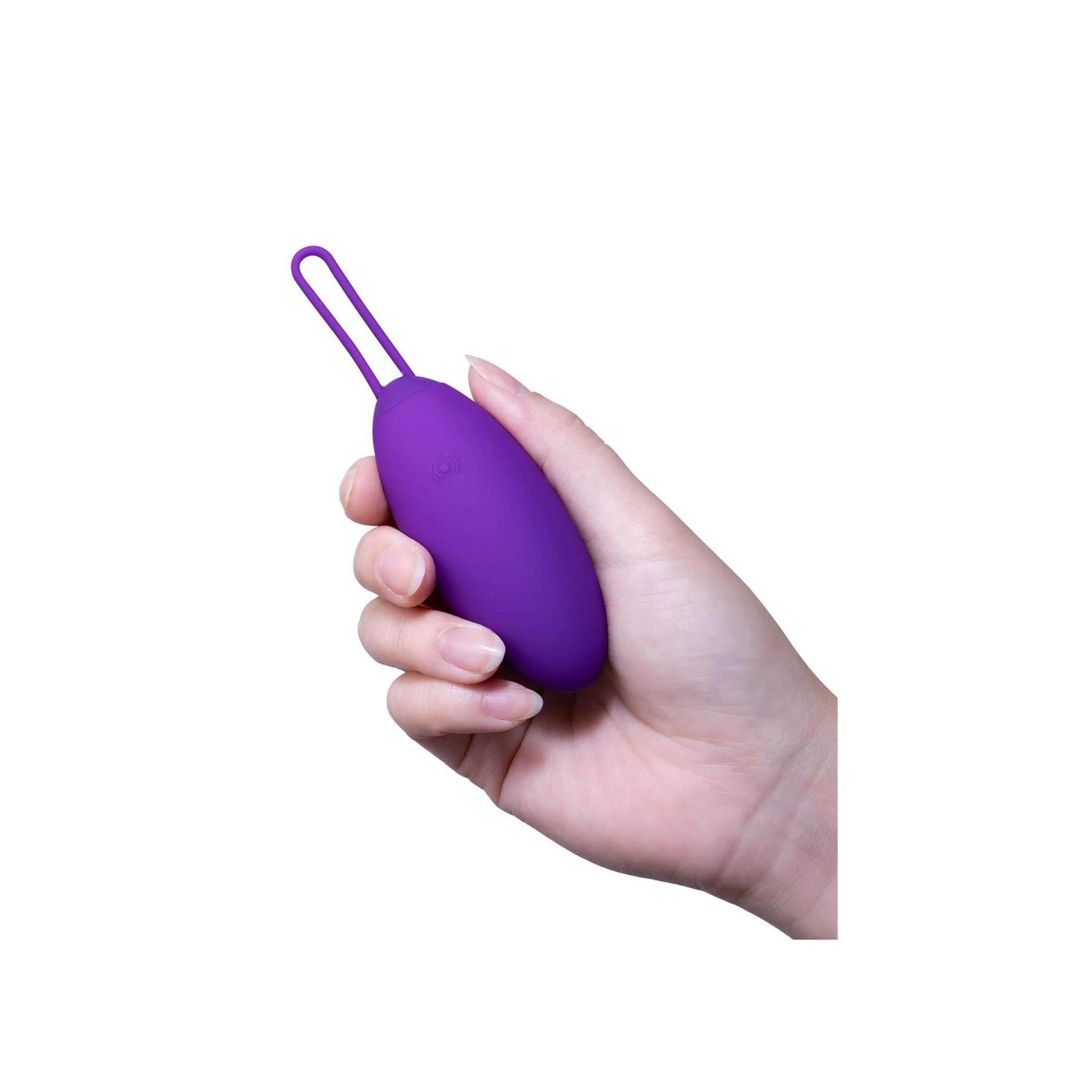 Hand hält lila Ei mit Schlaufe. Auf weißem Hintergrund.
