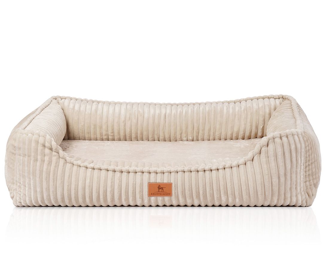 Beiges orthopädisches Hundebett mit erhöhten Seiten und einem rechteckigen Design. Cord-Optik mit Markenlogo.