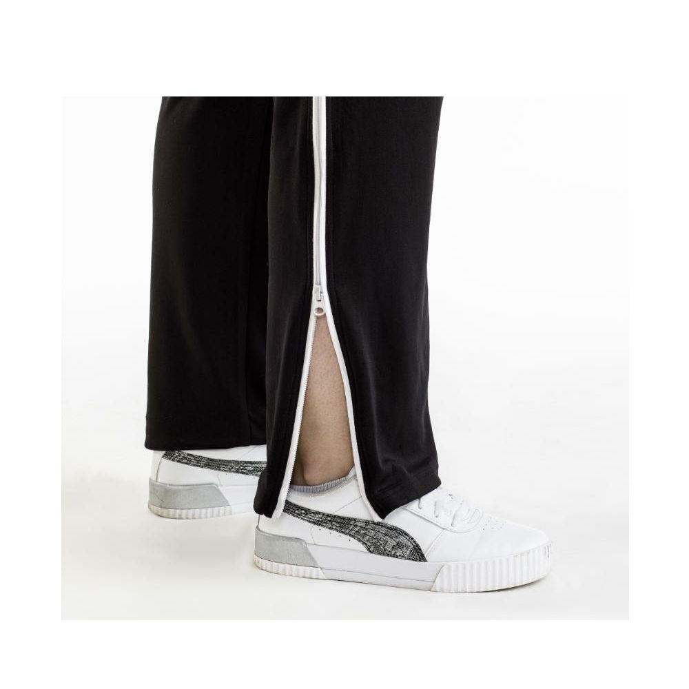Schwarze Therapiehose mit weißem Reißverschluss. Person trägt weiße Schuhe.