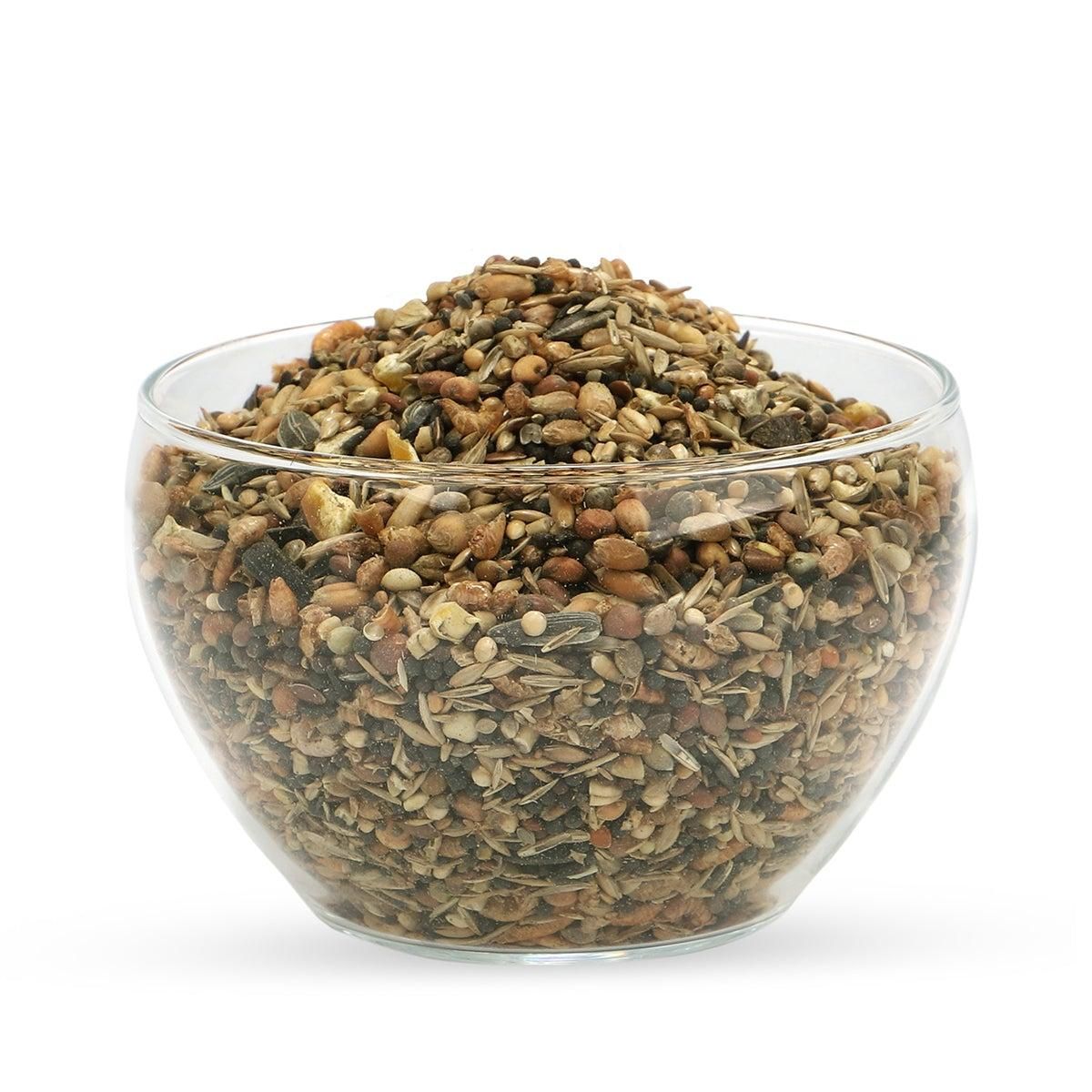 Transparente Glasschale gefüllt mit einer Mischung aus Samen und Körnern. Auf weißem Hintergrund.
