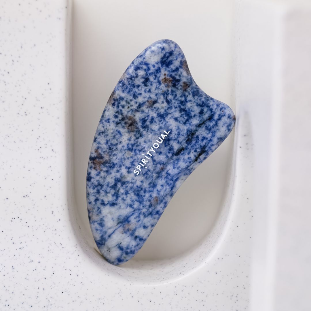 Blau-weißes Gua Sha aus Sodalith. In weißer Halterung platziert. Markenschriftzug SPIRITYOUAL.