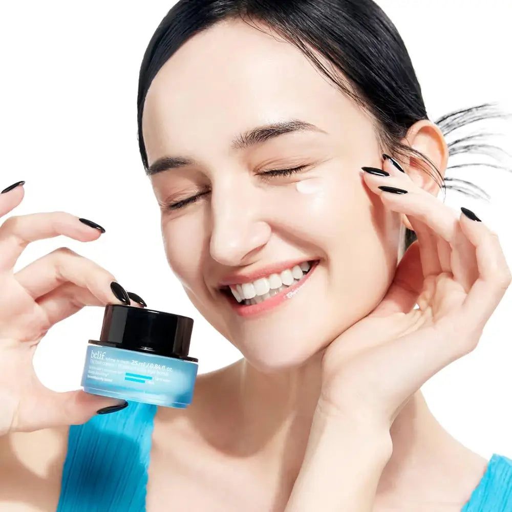 Frau hält einen blauen Tiegel mit einer Creme für die Augenpartie.