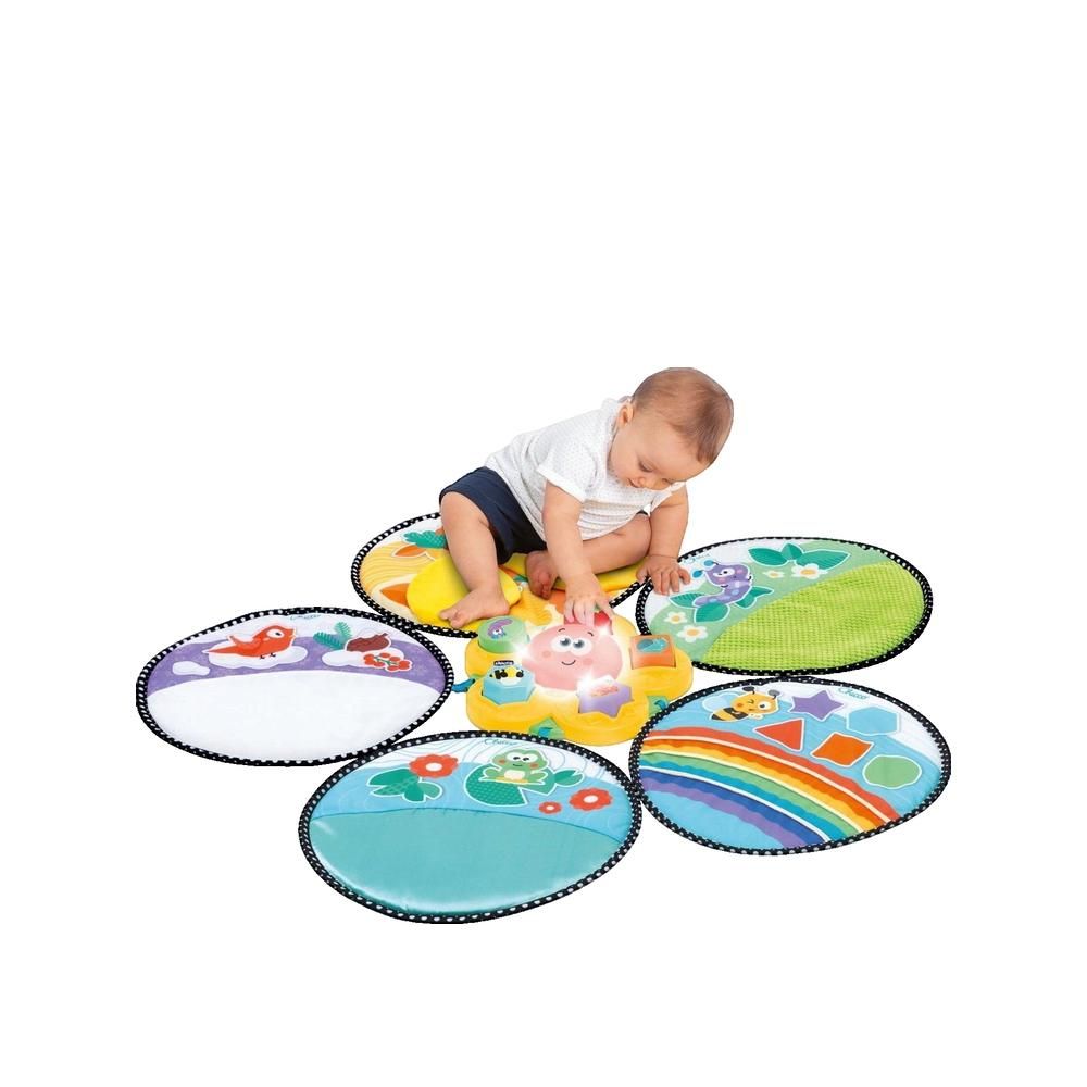 Sensorischer Teppich mit fünf ovalen Elementen. Baby sitzt auf dem gelben Element und spielt. Verschiedene Farben und Muster.