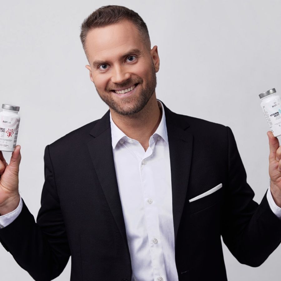 Ein Mann hält zwei Flaschen. Auf den Flaschen steht: BESTLAB, VITAMIN BEST. Der Mann lächelt in die Kamera.