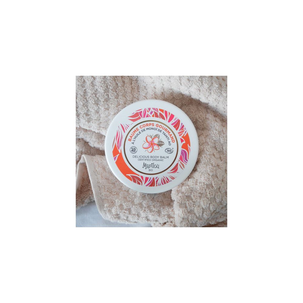 Körperbalsam-Tiegel auf einem Handtuch. Produkt mit floralem Design und Text. Zertifiziertes Bio-Produkt.