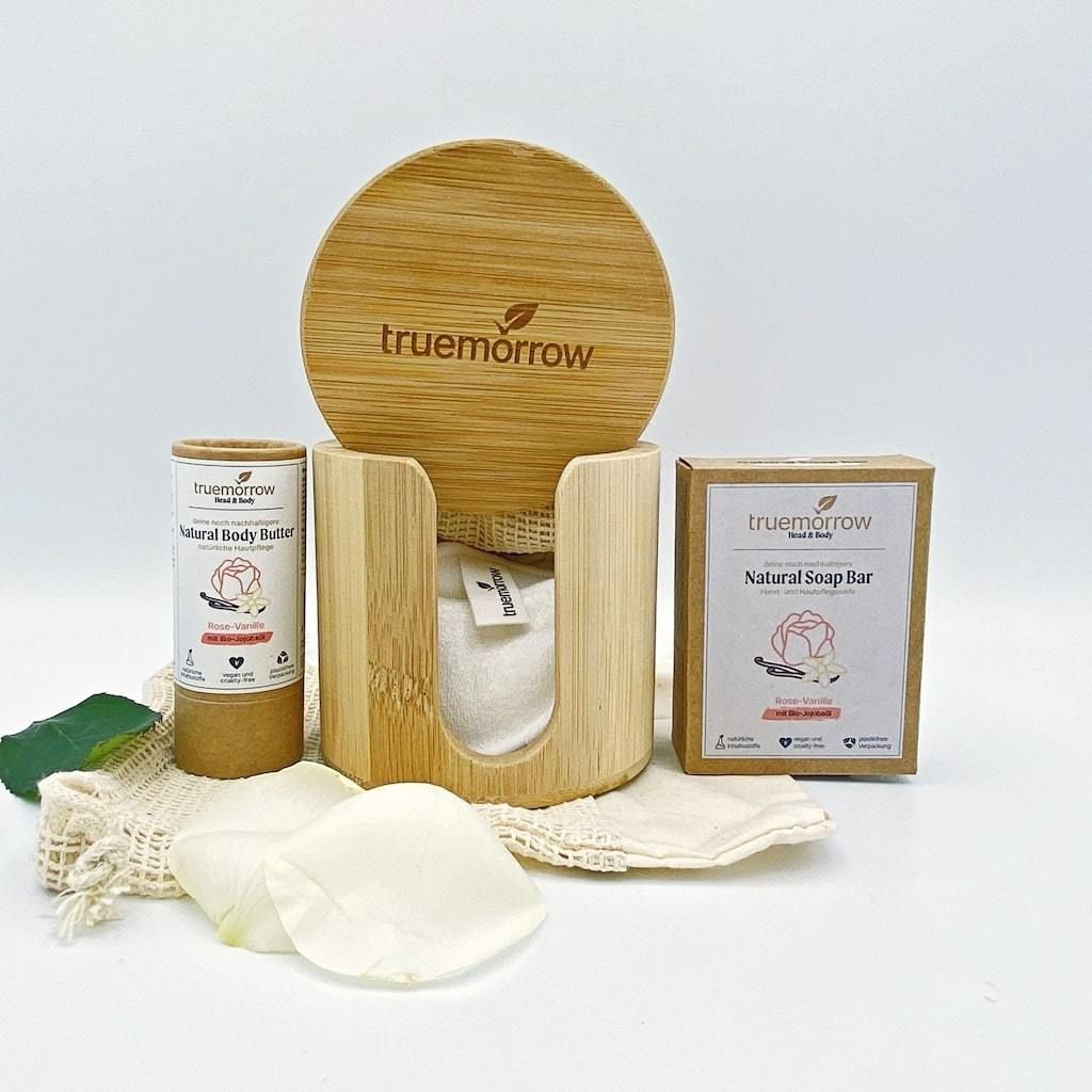 Geschenkset mit Seife und Body Butter. Enthält einen Bambus-Halter, eine Seife, eine Body Butter, ein Waschbeutel und Blütenblätter.