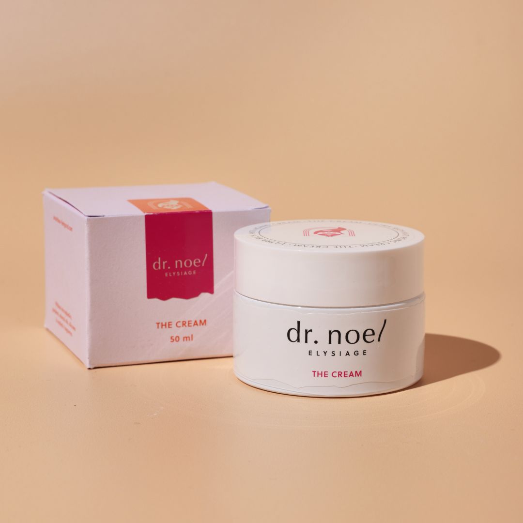 Creme-Glas und Box mit 'dr. noel/ ELYSIAGE THE CREAM' Aufschrift. Rosa Akzente.
