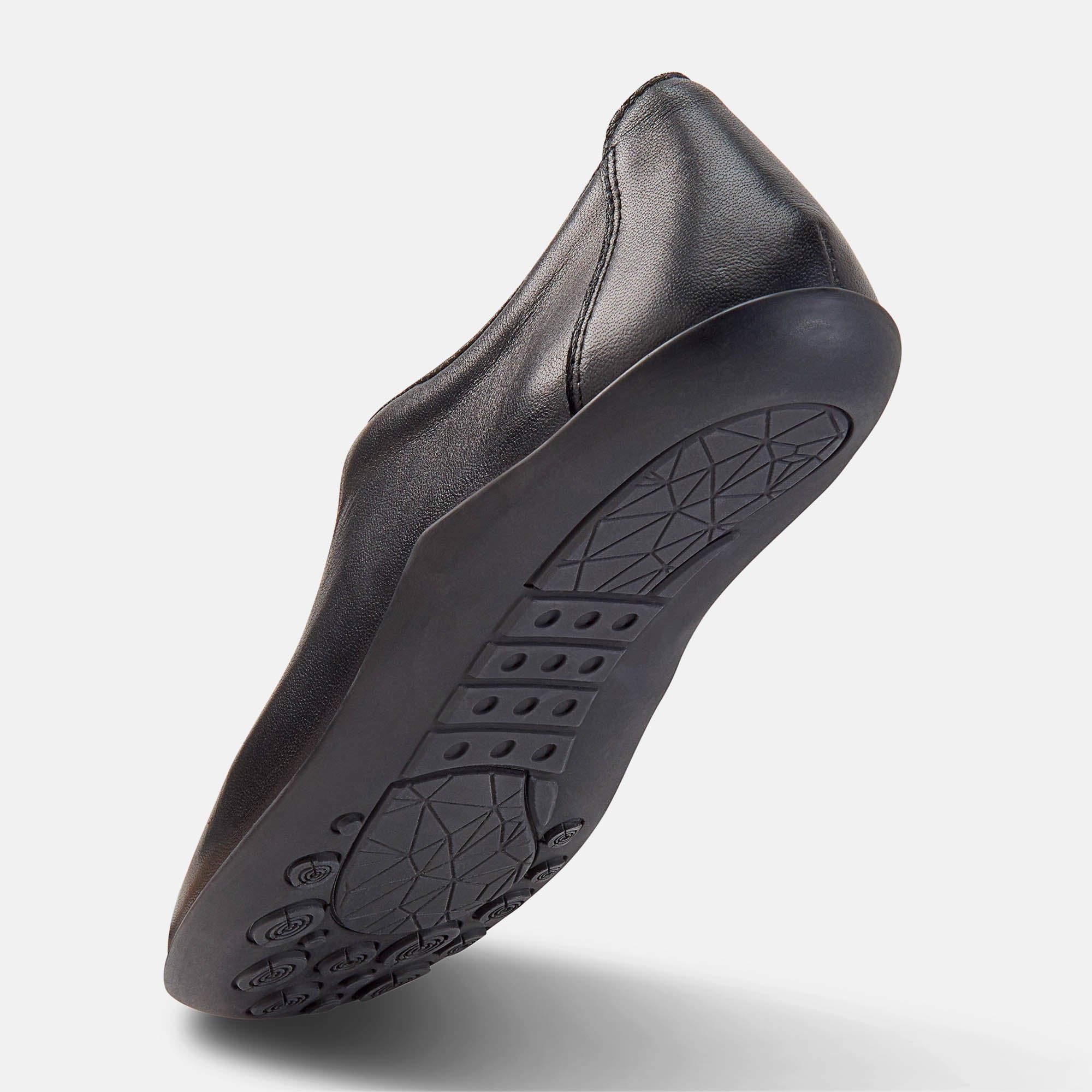 Schwarzer Damen-Slipper. Unteransicht der Sohle. Profilierte Gummisohle. Perspektivische Ansicht.