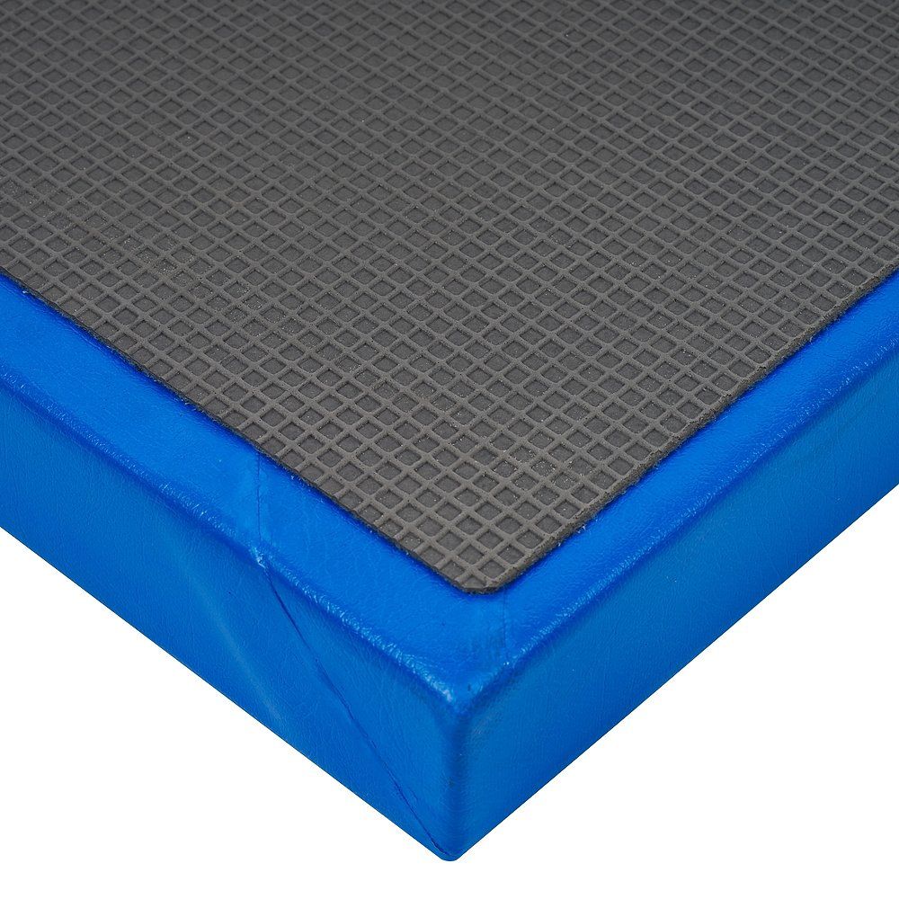 Nahaufnahme einer Turnmatte. Graue, strukturierte Oberfläche mit blauem Rand. Eckdetail sichtbar.