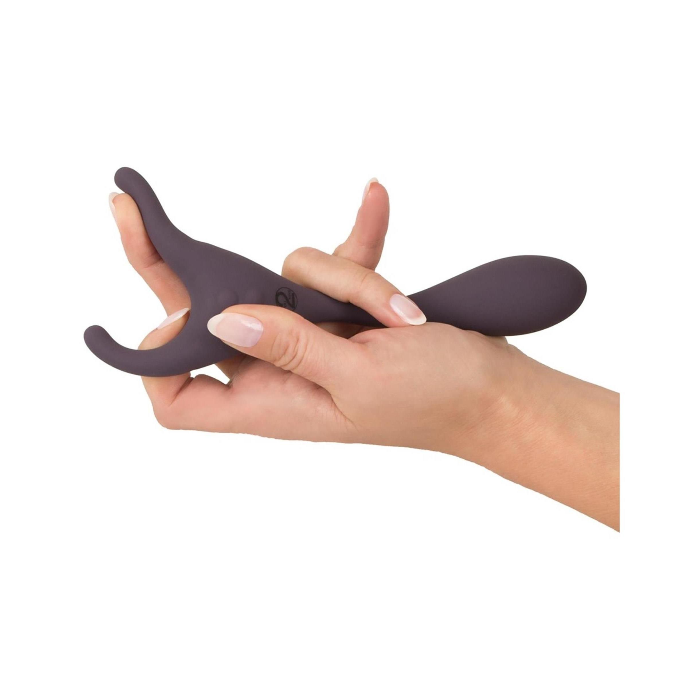 Hand hält lila Vibrator. Geschwungene Form. Glatte Oberfläche. Ringförmiger Teil.