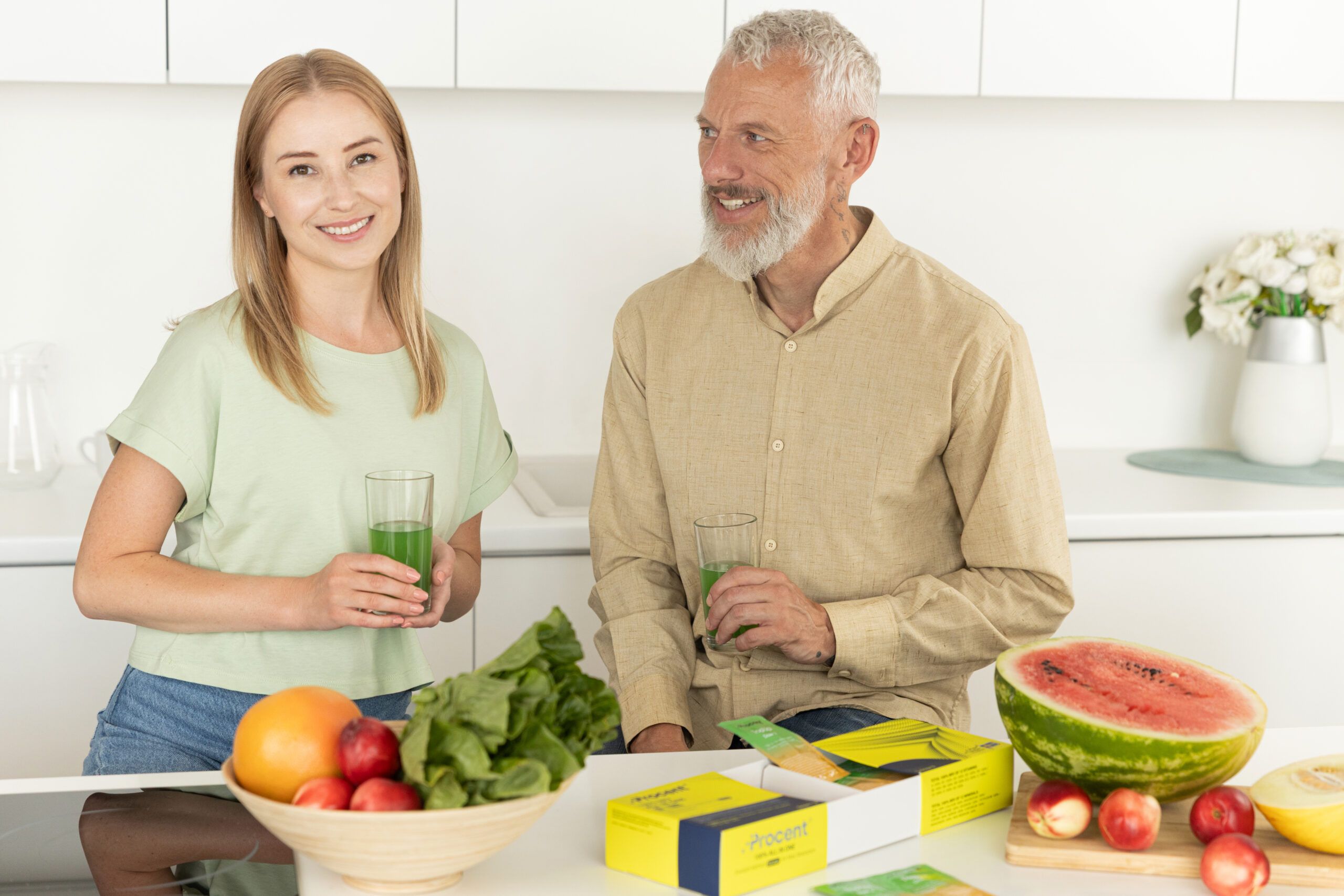 Frau und Mann mit Getränken und Obst. Auf dem Tisch: PROCENT-Box, Obstschale, Wassermelone.