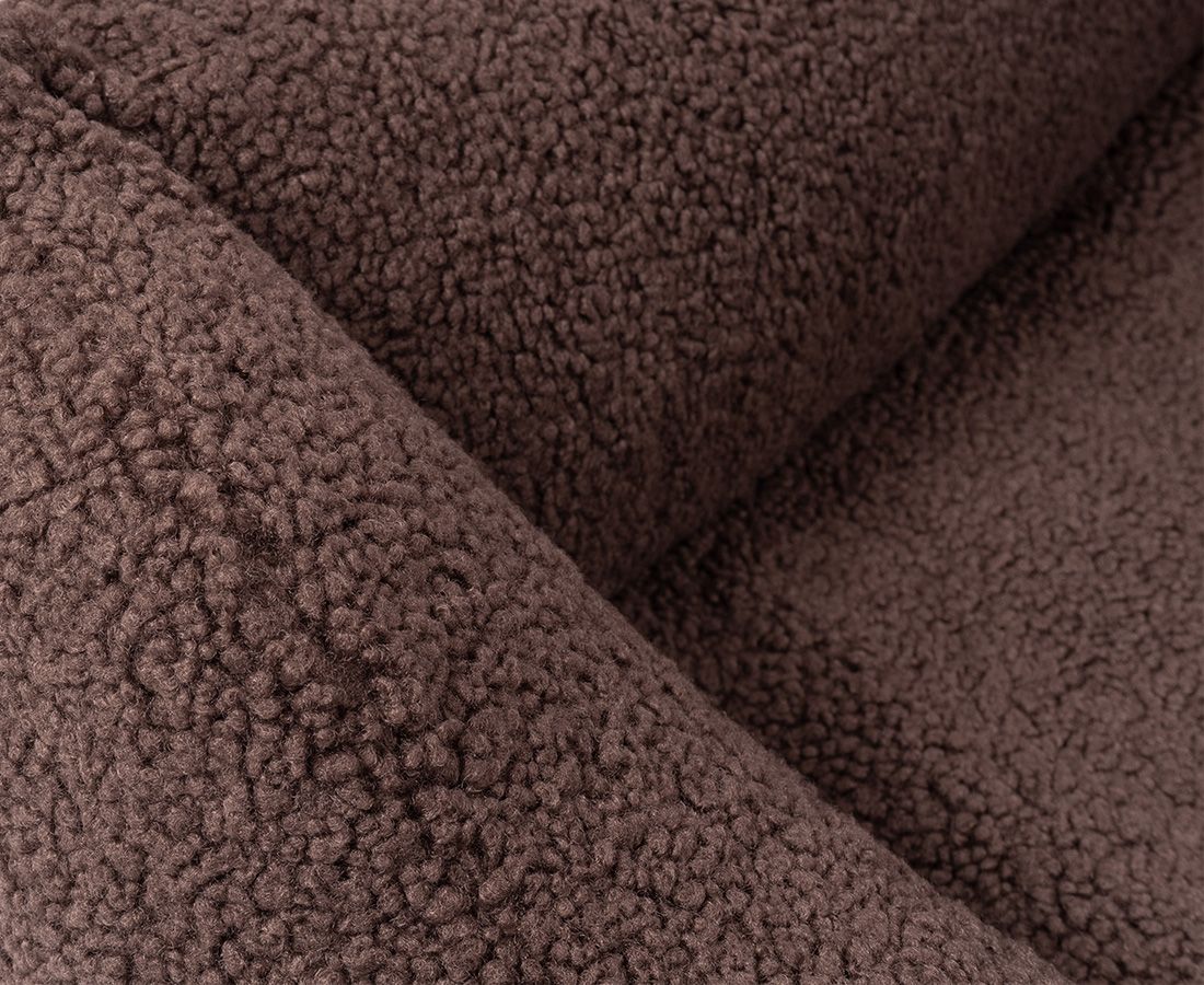 Nahaufnahme des braunen, strukturierten Materials eines orthopädischen Hundebetts. Weiche, flauschige Textur. Falten sichtbar.