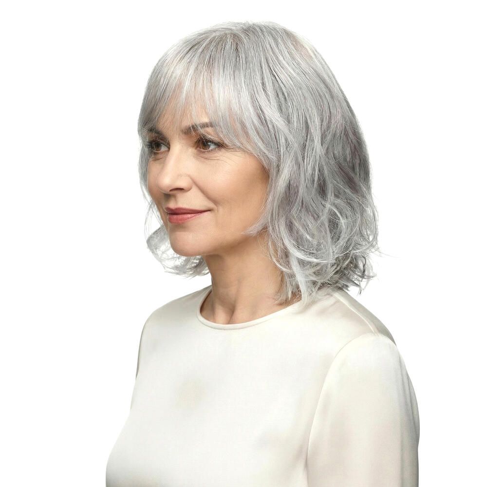 Perücke Capri, graues Haar mit Pony, wellig. Frau im Profil, helles Oberteil.