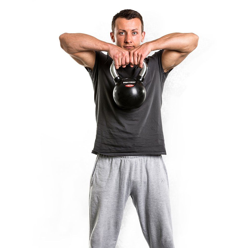 Mann hebt eine 4kg Kettlebell vor dem Körper, Hände am Griff.