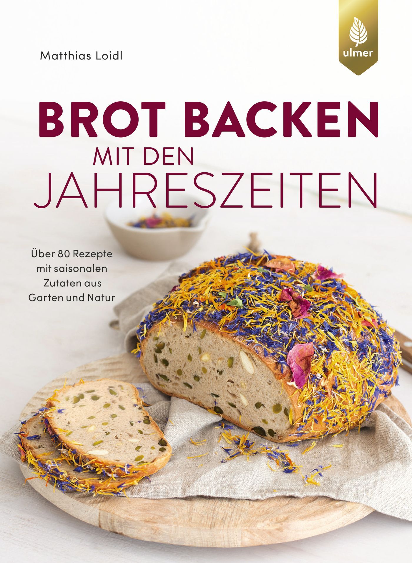Buchcover: Brot Backen mit den Jahreszeiten. Brot mit Blüten auf Holzbrett. Autor: Matthias Loidl. Verlag: ulmer. Über 80 Rezepte mit saisonalen Zutaten.