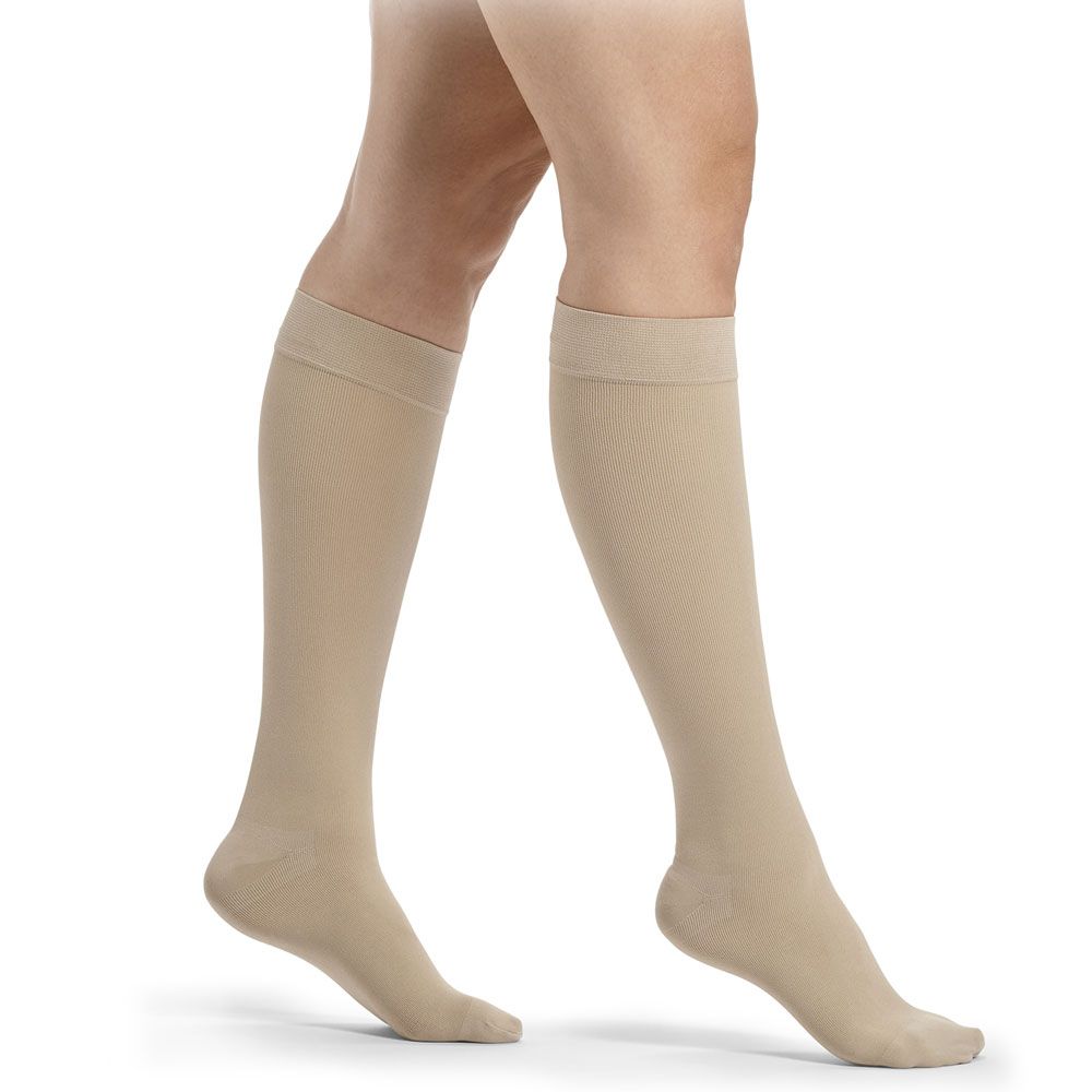 Beige Kompressionsstrümpfe bis zum Knie, glatt gestrickt, mit breitem Bündchen.