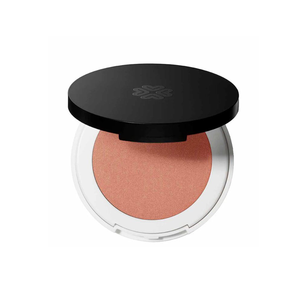 Runder, kompakter Rouge-Puder mit schwarzem Deckel. Der Puder ist pfirsichfarben und in einer weißen Hülle.