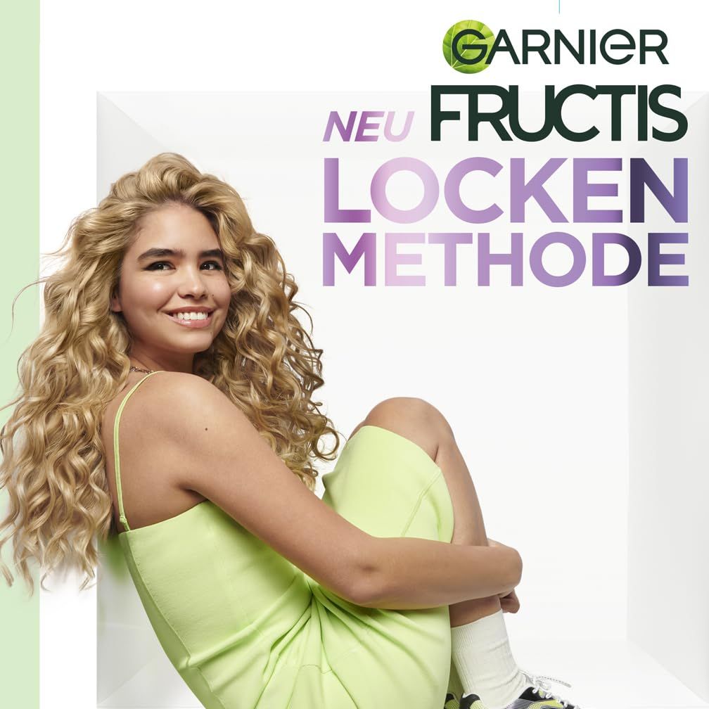 Junge Frau mit lockigem Haar. Text: Garnier Fructis Locken Methode. Frau sitzt in weißem Rahmen.