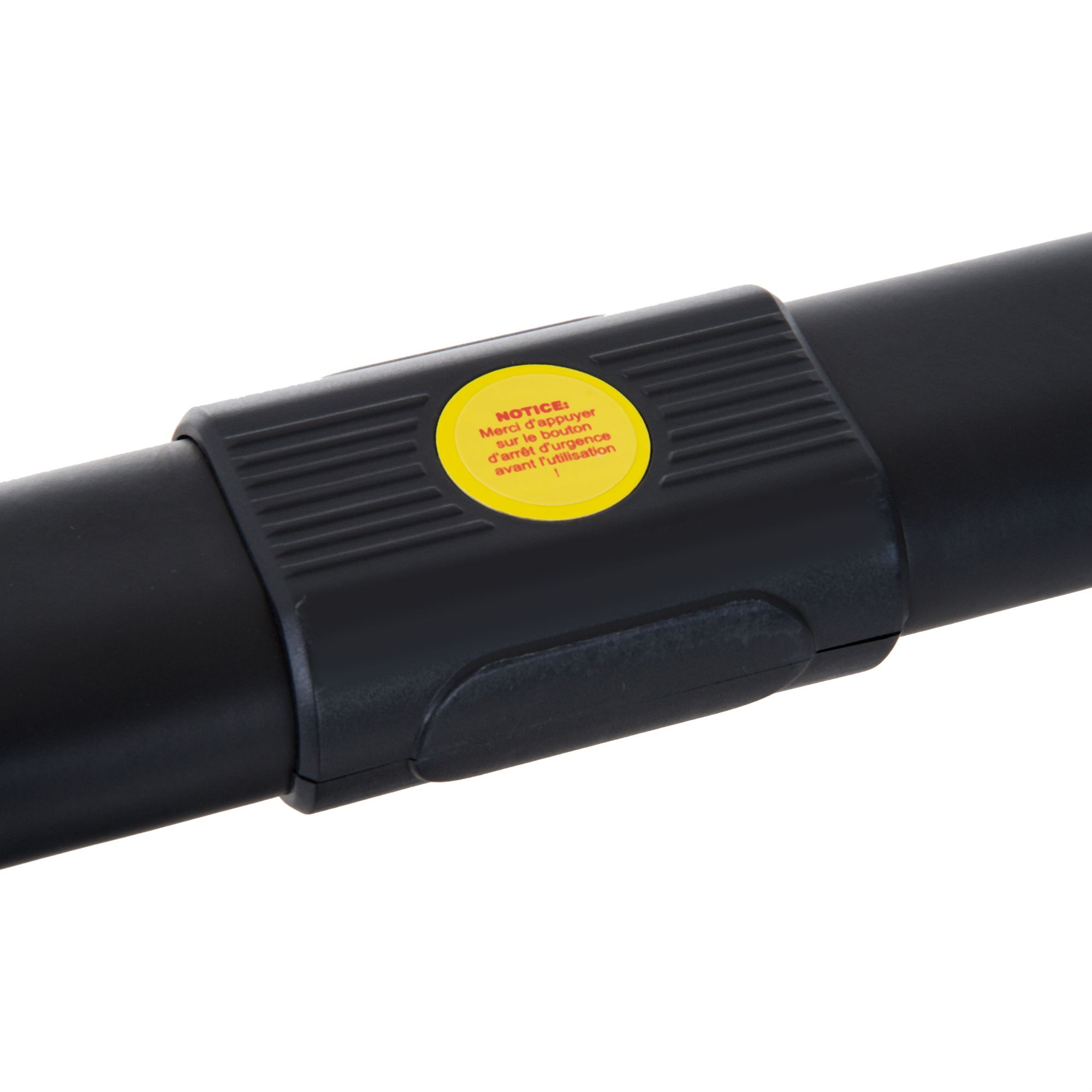 Nahaufnahme eines schwarzen Gelenks am Laufband. Gelber Aufkleber mit Text: 'NOTICE: Ne pas appuyer...'.