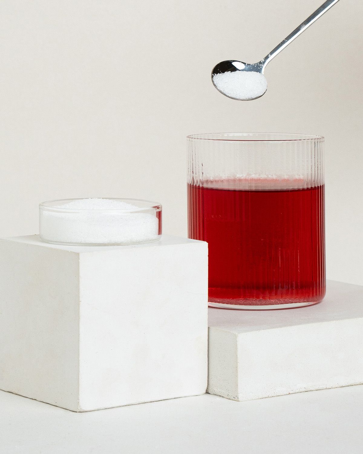 Erythritol auf einem Löffel über einem Glas rotem Getränk.