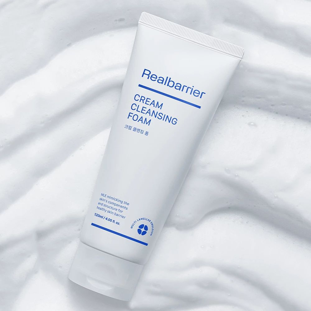 Weiße Tube mit blauem Schriftzug Realbarrier, Cream Cleansing Foam, auf Schaum gelegt.