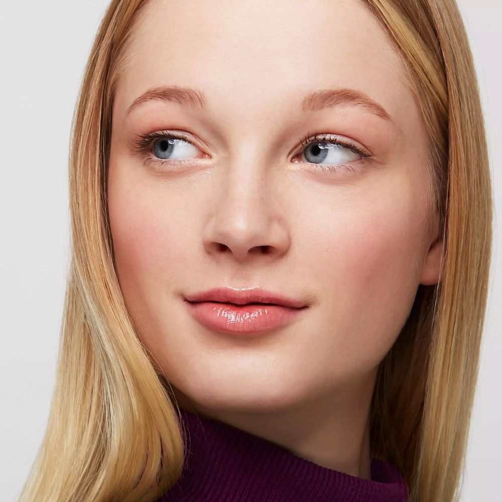 Porträt einer Frau mit blonden Haaren. Sie trägt ein dunkelviolettes Oberteil. Augenbrauen sind leicht betont.