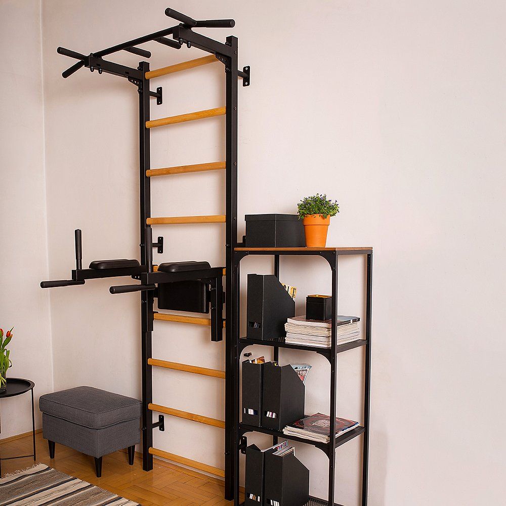 Klimmzugstange mit Dip-Station an einer Wand. Schwarzer Metallrahmen, Holzsprossen. In Wohnraum.