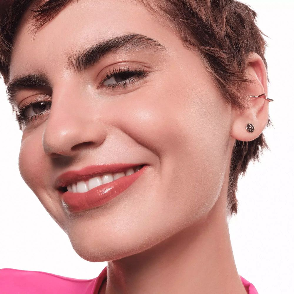 Porträt einer Frau mit rosafarbenem Lippenstift. Sie lächelt.