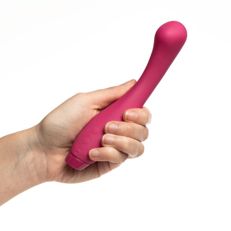 Rosa Vibrator in einer Hand gehalten. Drei Knöpfe sichtbar. Weißer Hintergrund.